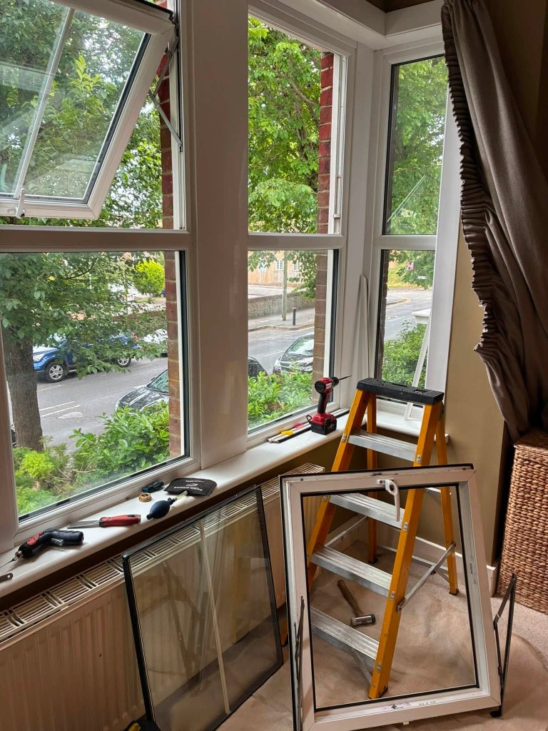 uPVC window repair setup with tools, step ladder, and removed glass unit by ASL Locksmiths Eastbourne.