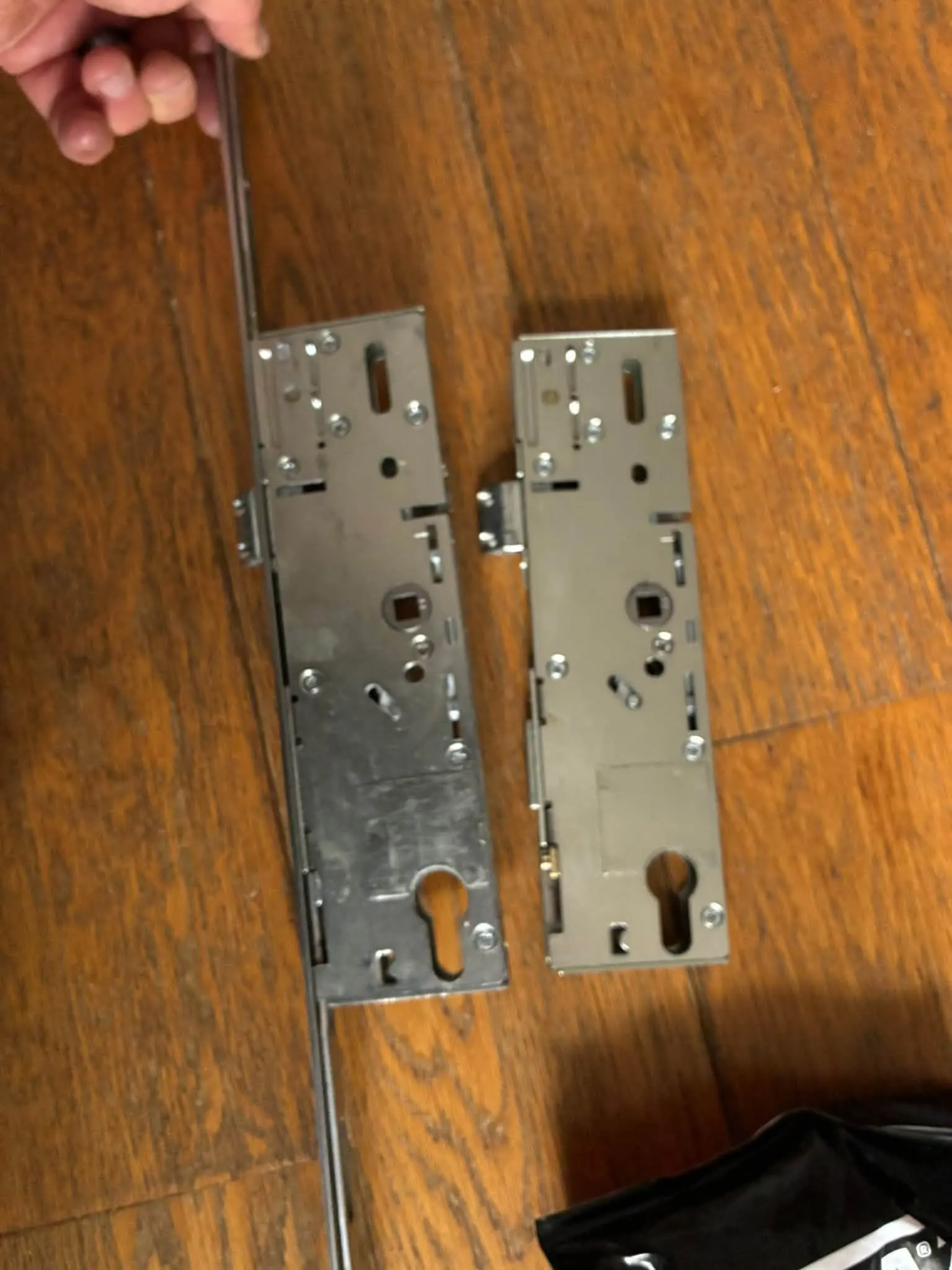 Replacement multipoint door lock gearbox side-by-side with the old unit on a wooden floor in Hellingly.